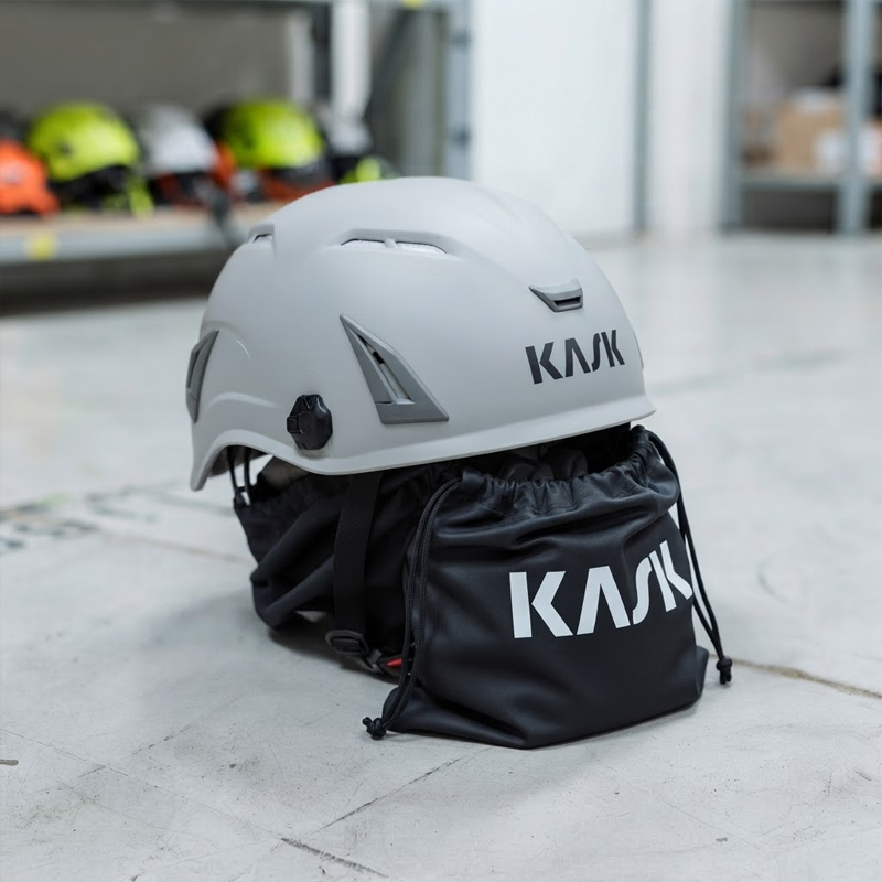 Grauer Kask Schutzhelm mit Belüftungsschlitzen und schwarzem Kask Aufbewahrungsbeutel auf Werkstattboden