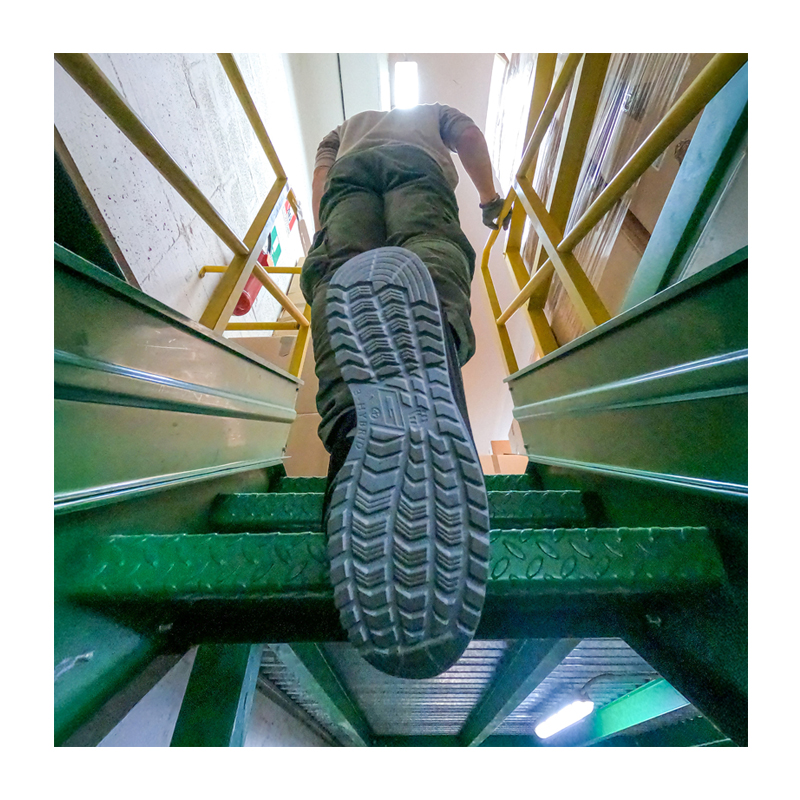 Arbeiter steigt eine Industrietreppe hinauf, Fokus auf die profilierte Sohle des Giasco 3Hybrid ESD Las Vegas S1PL Sicherheitsschuhs mit max. Dämpfung, metallfrei und rutschhemmend.