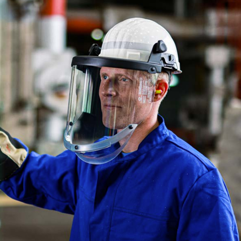 Mann mit weißem Schuberth Schutzhelm und klarem Gesichtsschutz bei der Arbeit im industriellen Umfeld