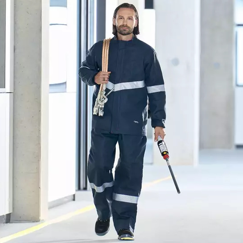 Arbeiter in dunkler Dehn Schutzbekleidung mit Reflexstreifen, trägt Seil und Prüfgerät im modernen Industriegebäude