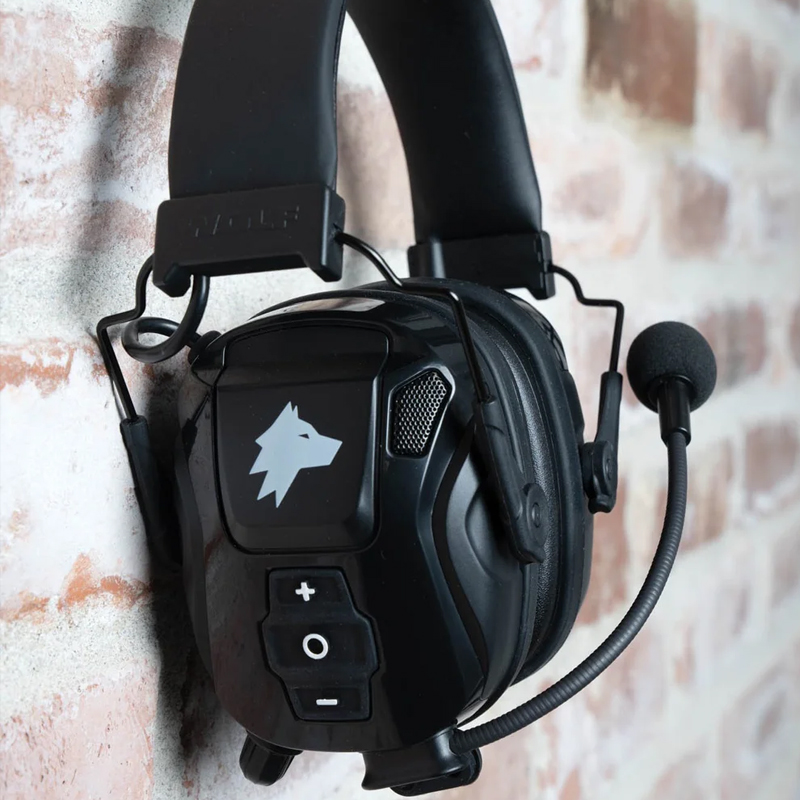 Schwarzes Wolf Protection Gehörschutz-Headset mit Mikrofon und Bedientasten, an einer Wand hängend